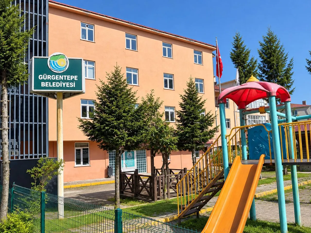 Özel Atahan binası, önünde çam ağaçları ve çocuk oyun parkı
